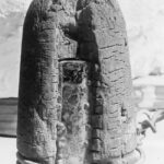An ancient, weathered artifact resembling a stone with lines and patterns.